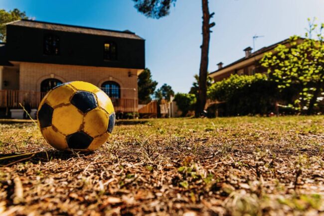 Close-up of an old worn football ball in the yard of a house.